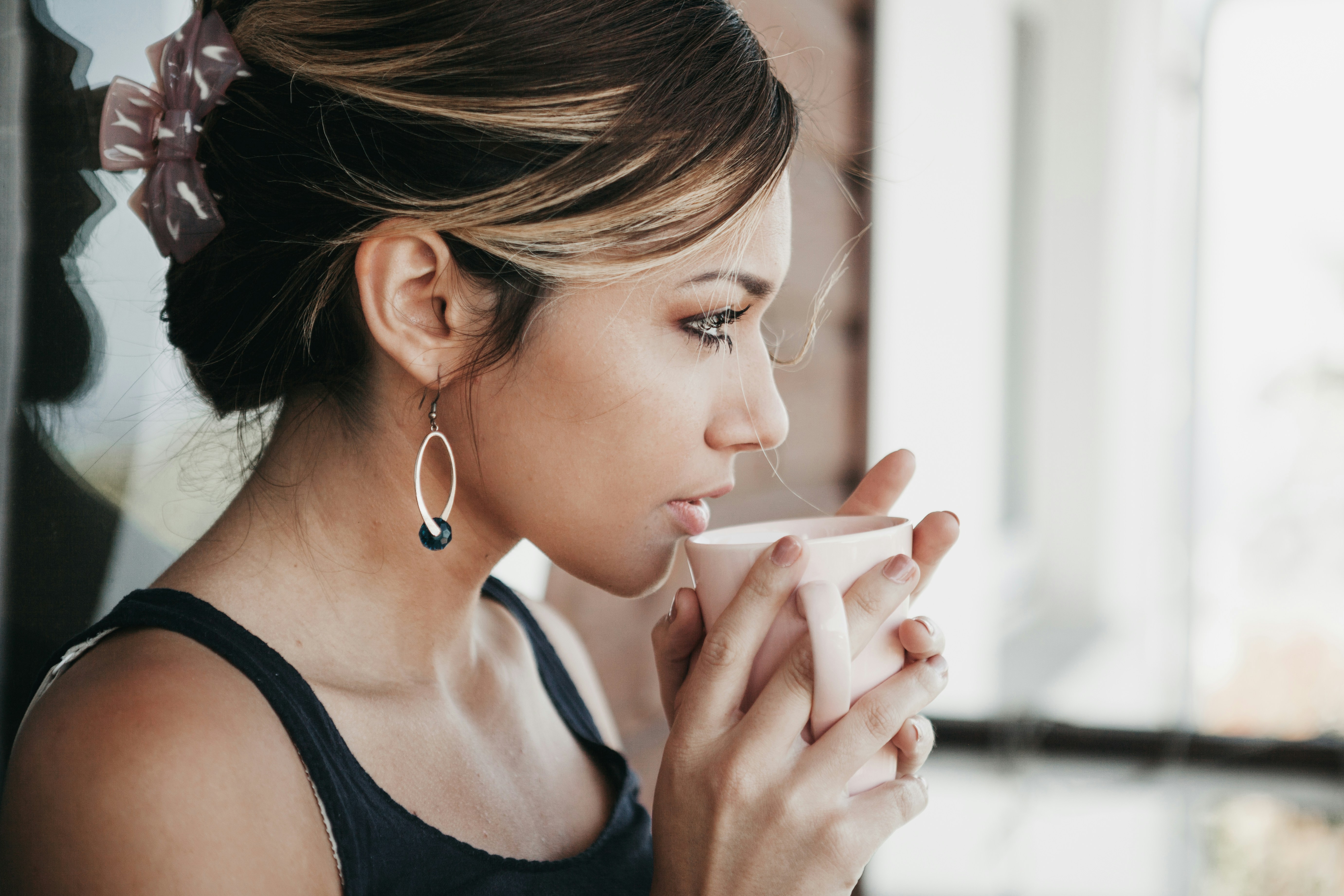 A person sitting quietly by a window with a warm cup of tea, looking thoughtfully outside — representing the quiet, often invisible emotional weight of the IVF journey.