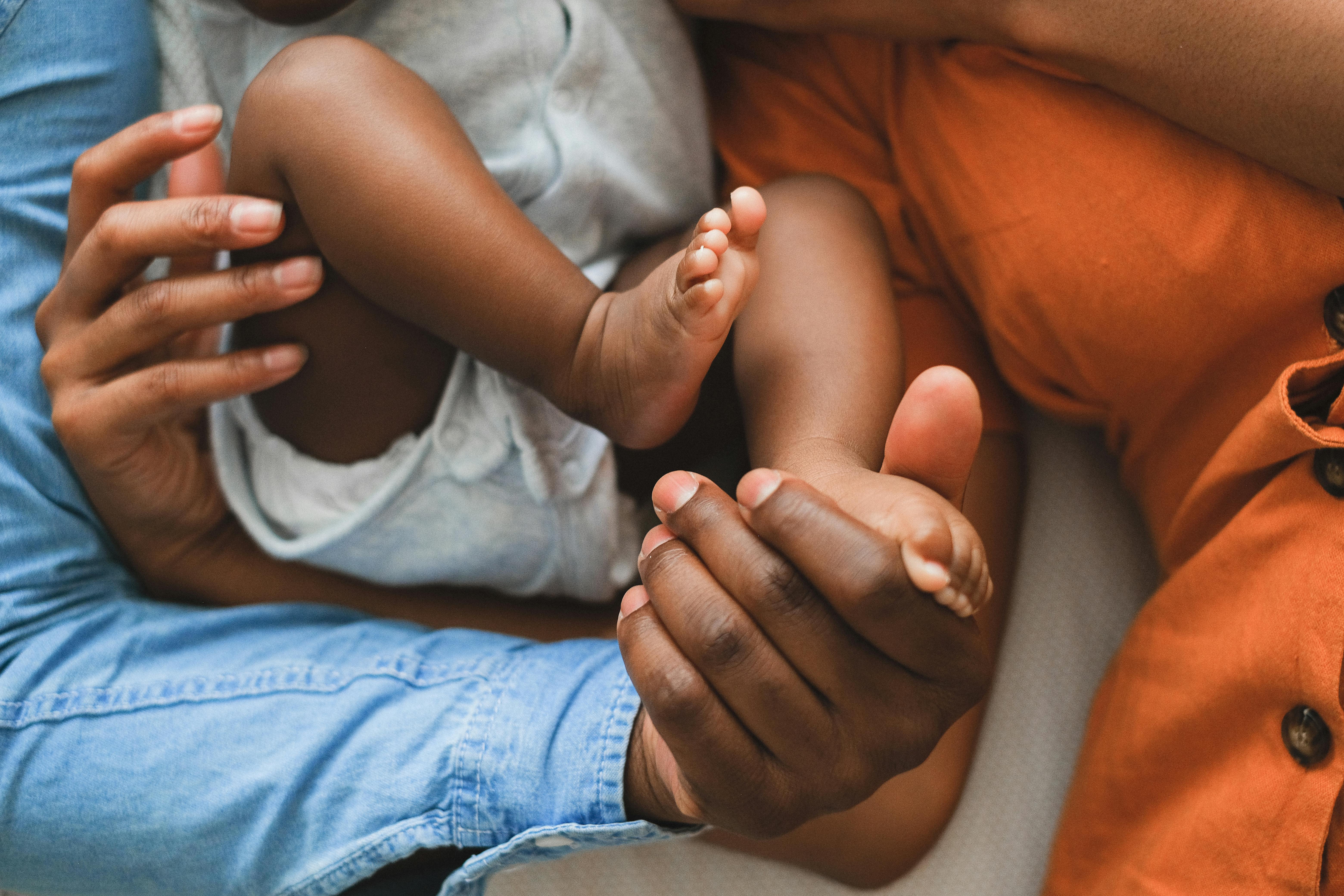 Parent holding sleeping newborn in a nursery, soft morning light
